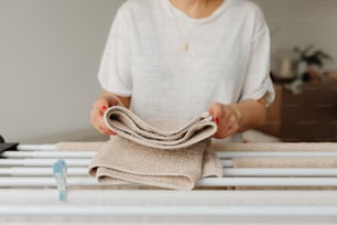 a woman holding a cloth over a bed rail