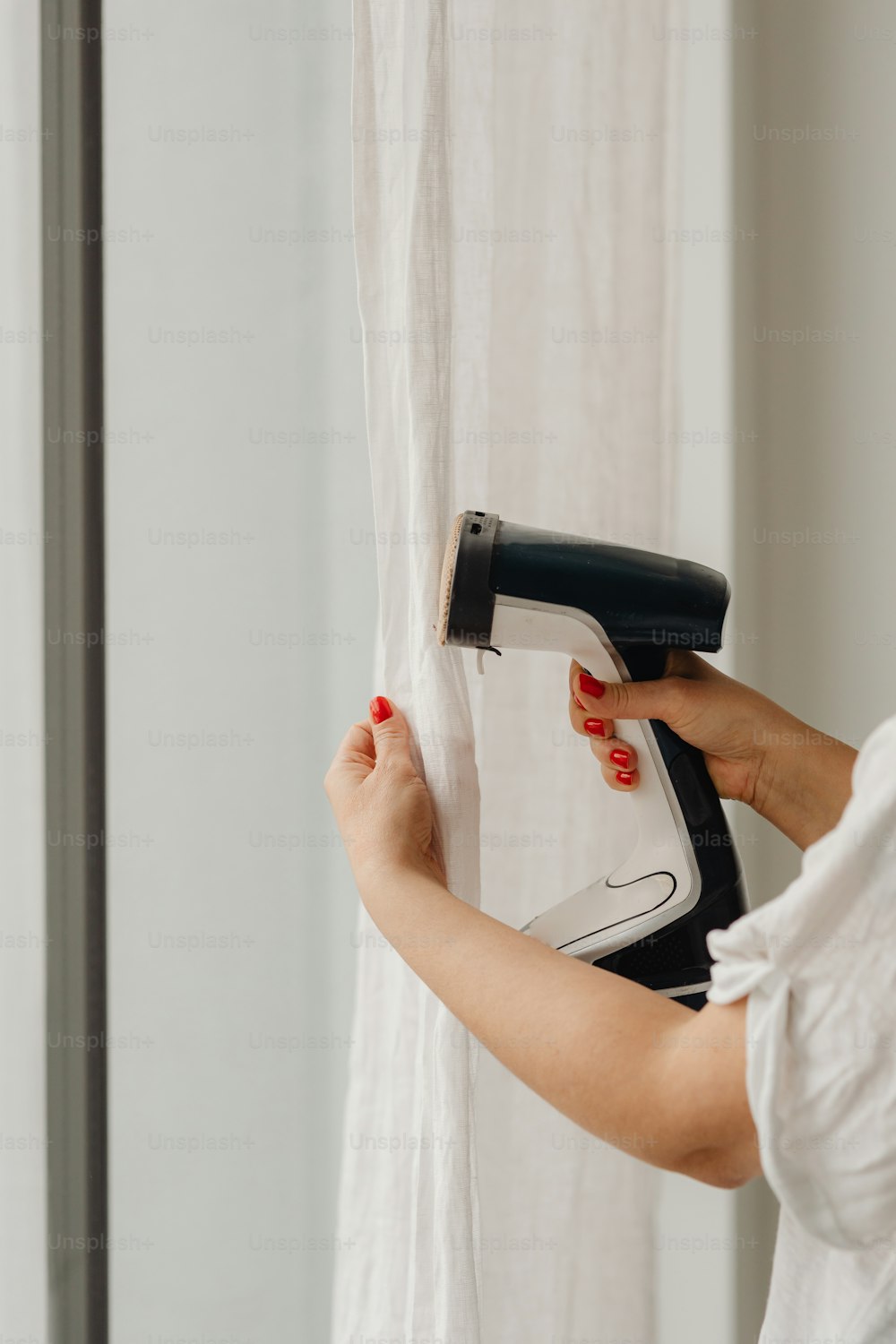 a woman is using a hair dryer to dry her hair