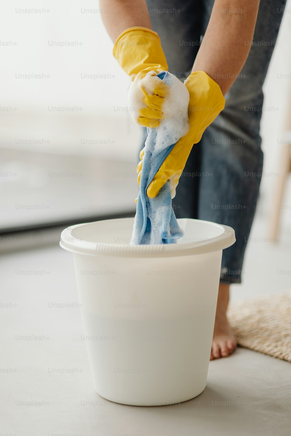 Una persona con guantes amarillos y guantes amarillos limpiando un cubo blanco