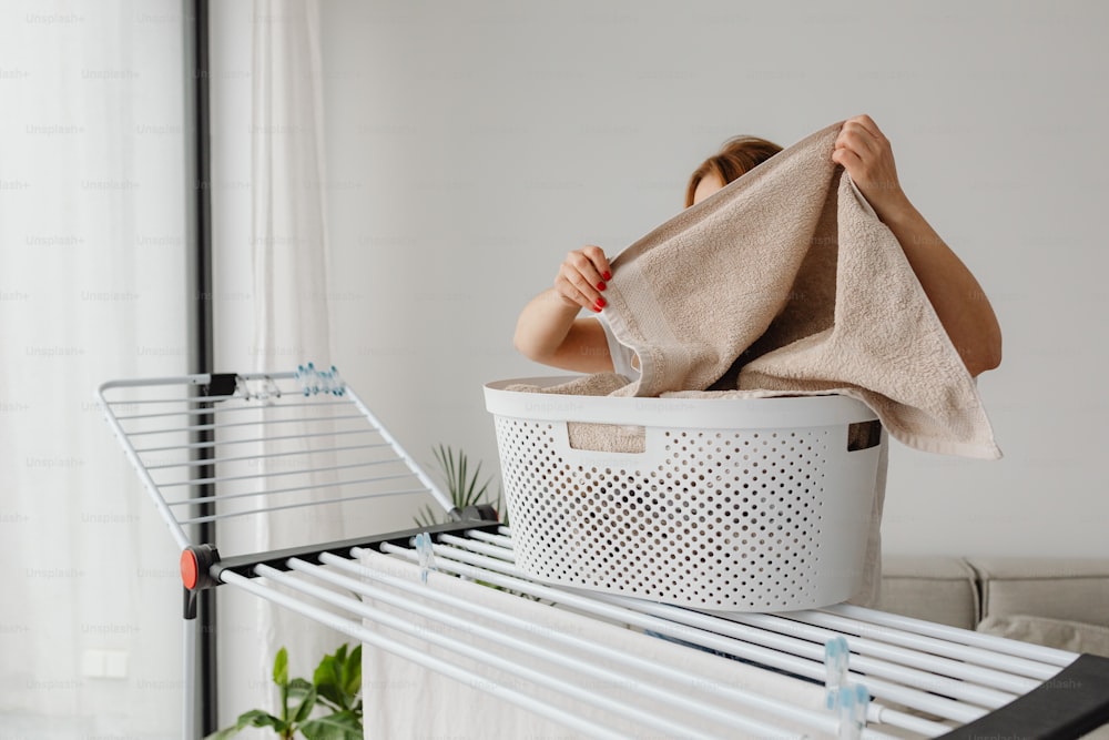 uma mulher está secando suas roupas em um cesto de roupa suja