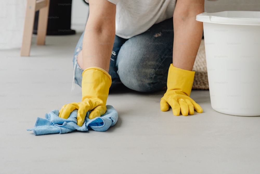 a person in yellow gloves cleaning a floor