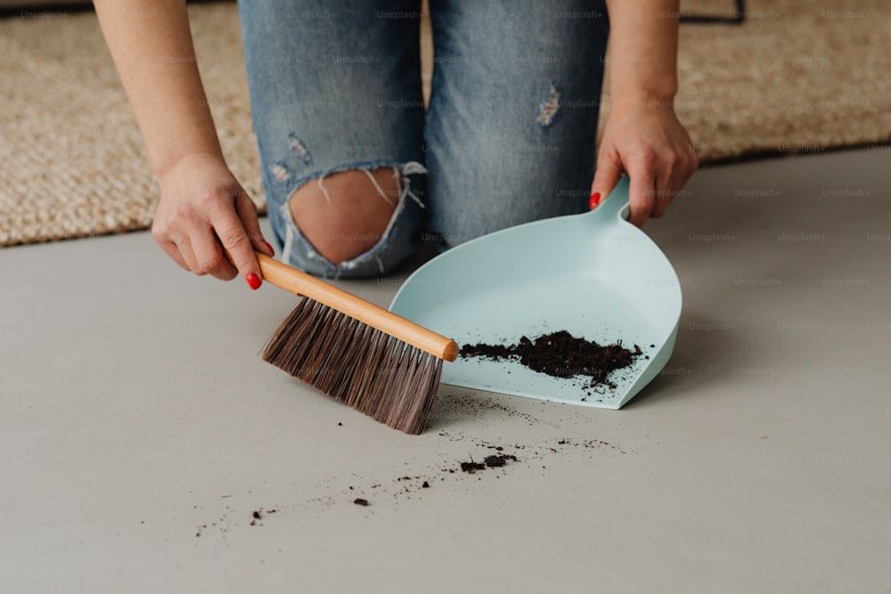 a woman is cleaning a floor with a dustpan and brush