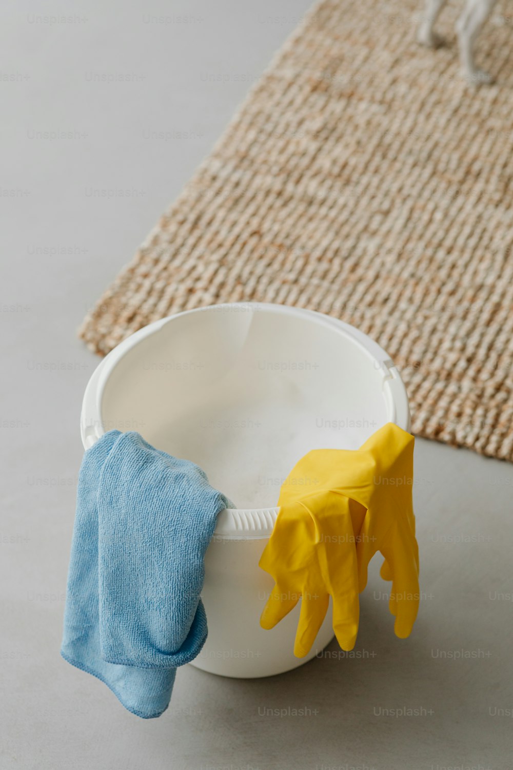 a pair of yellow gloves and a blue cloth in a white bowl