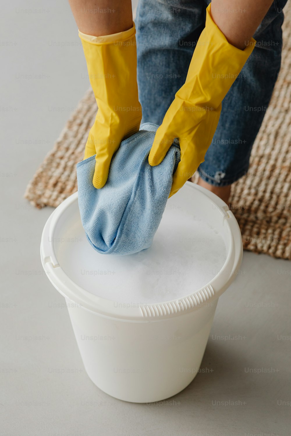 une personne portant des gants jaunes nettoyant un seau