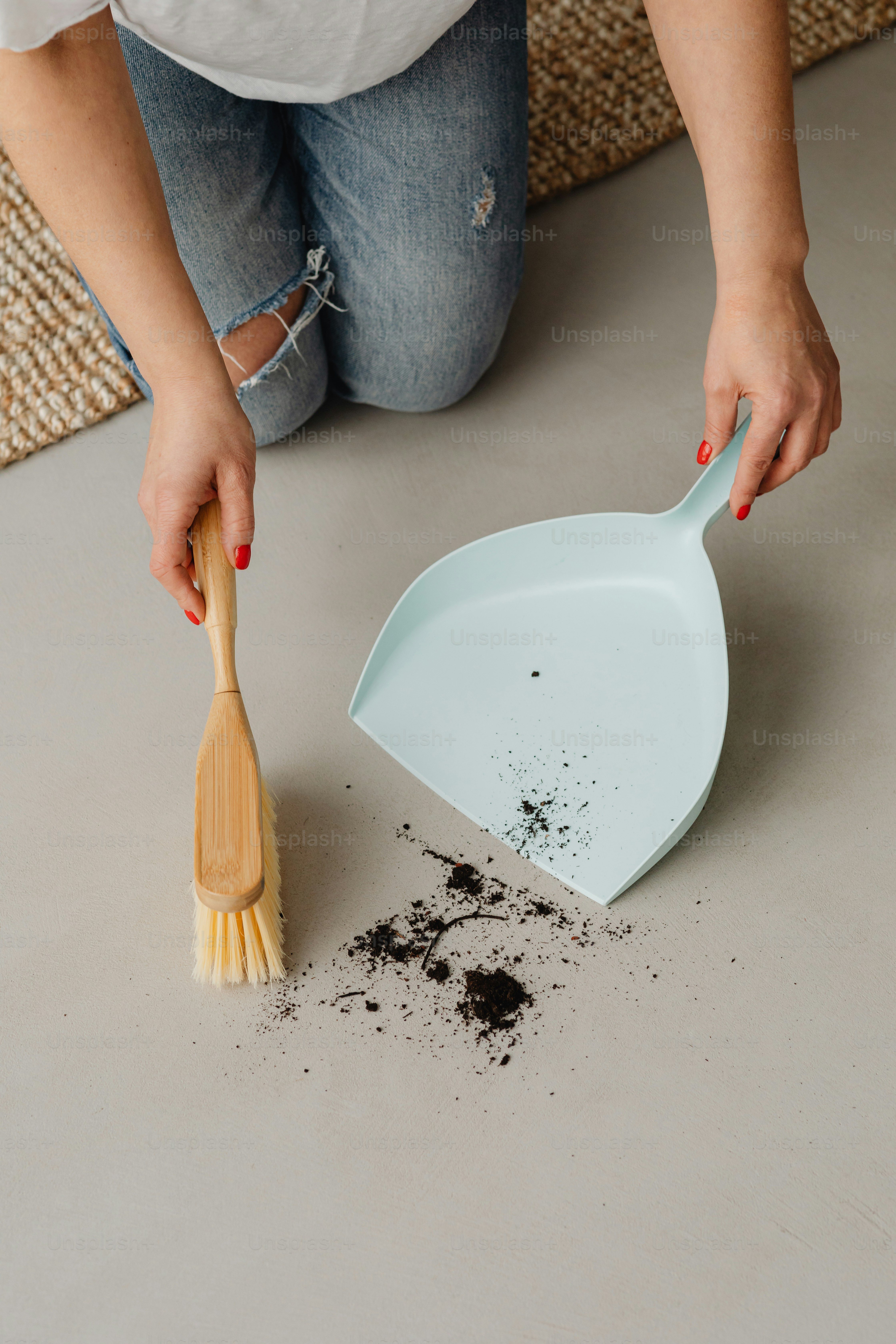 a woman scooping dirt off of a floor with a spatula