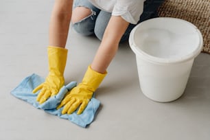 a woman cleaning a floor with a yellow glove