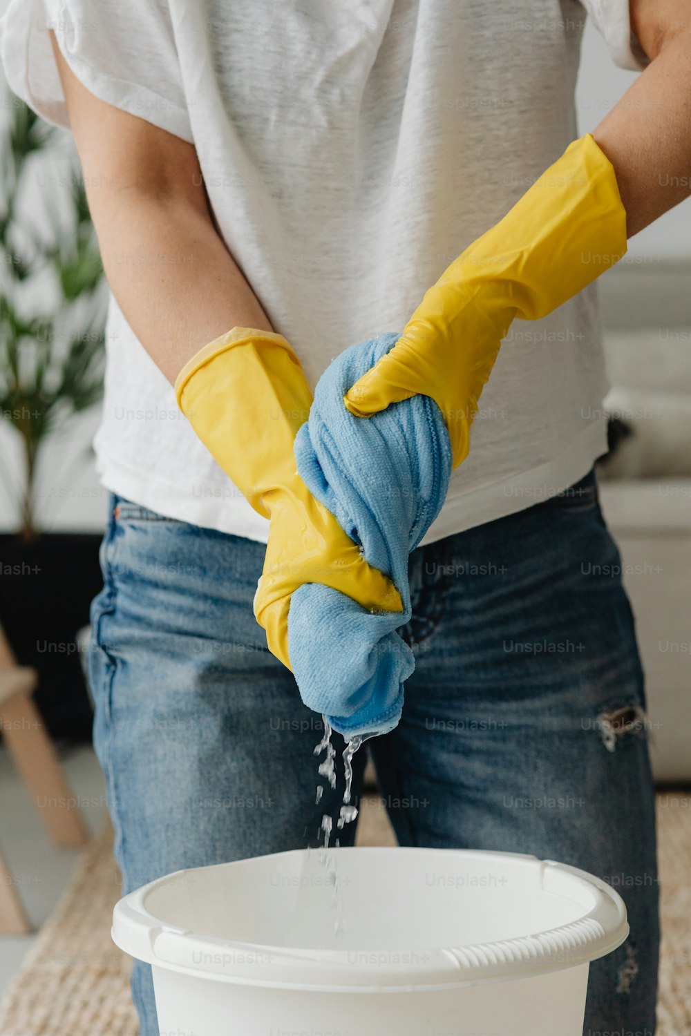 a person in yellow gloves is washing a bucket