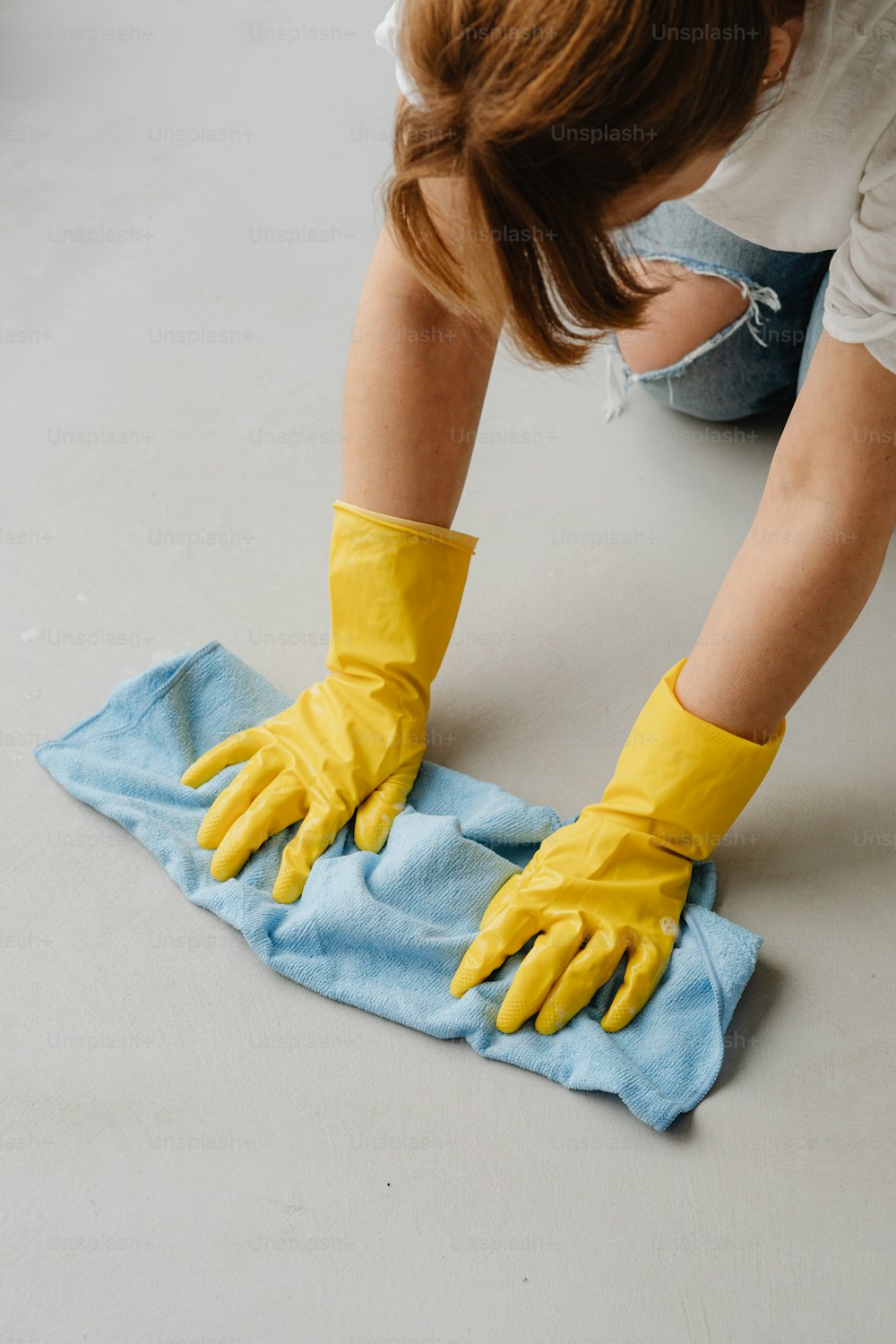 a woman in yellow gloves wiping up a blue towel