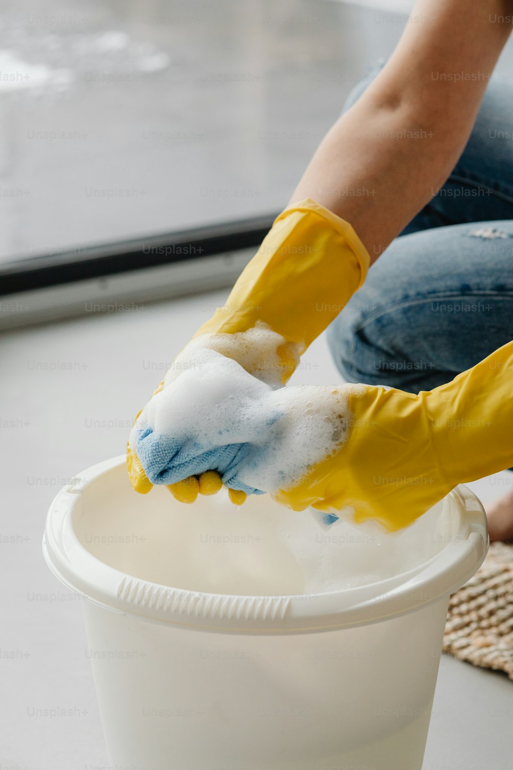 a person in yellow gloves cleaning a white bucket