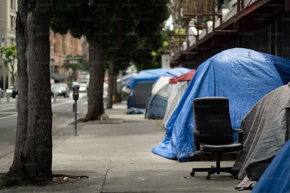 uma cadeira sentada em uma calçada ao lado de um monte de tendas