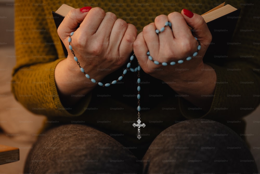 a woman wearing a rosary and holding a book