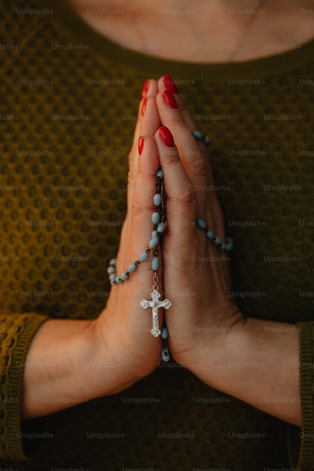 Una mujer sosteniendo un rosario en sus manos
