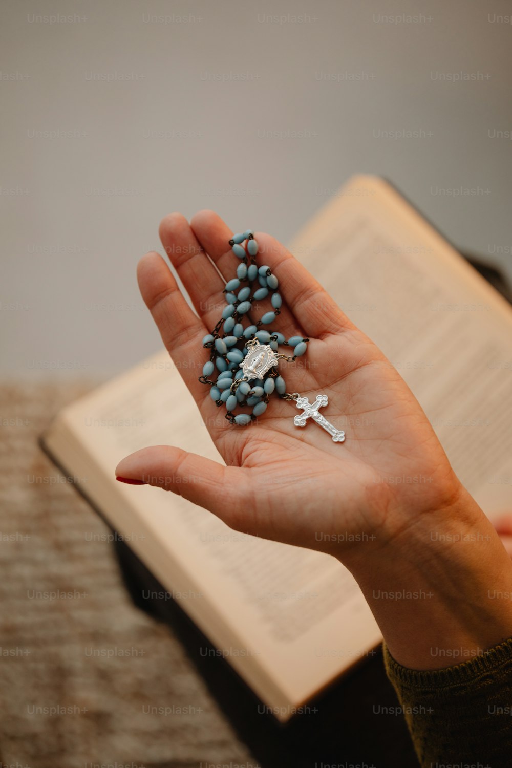 una persona sosteniendo un rosario y un libro