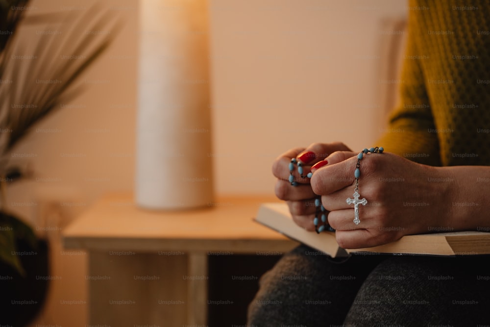 a woman sitting on a chair holding a rosary