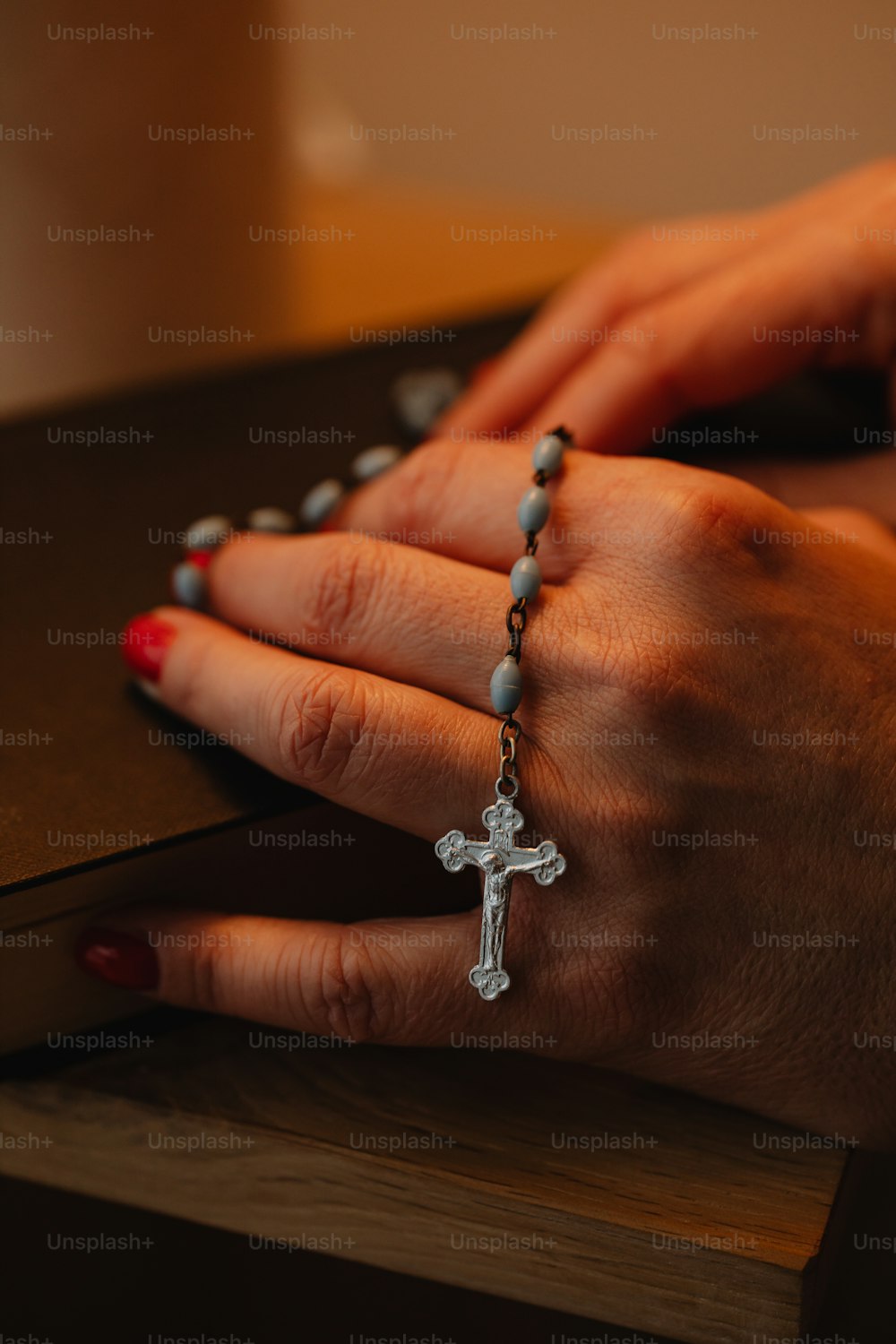 die Hände einer Frau, die einen Rosenkranz mit einem Kreuz darauf hält