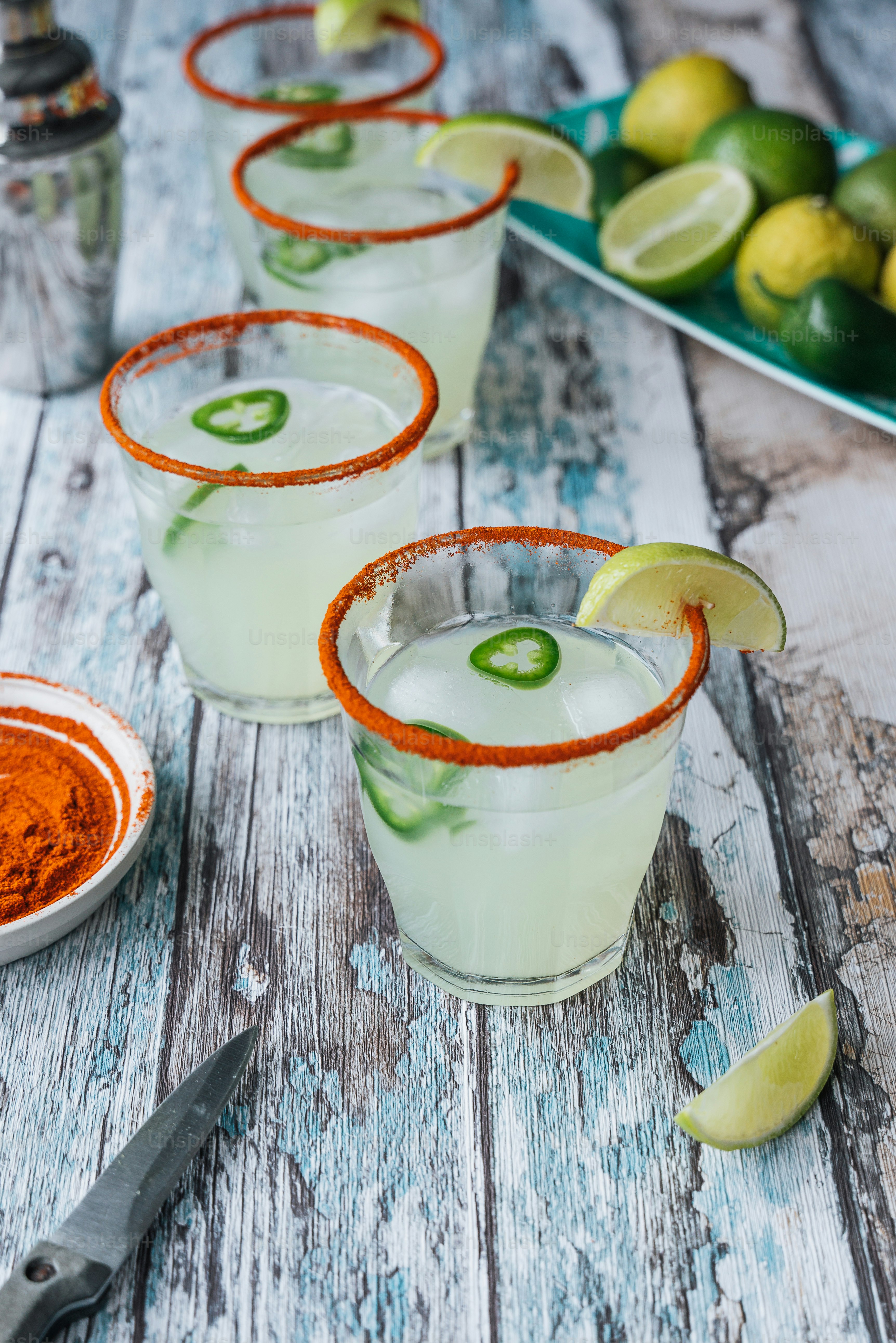 três copos de margarita margaritas com limas e limas ao fundo