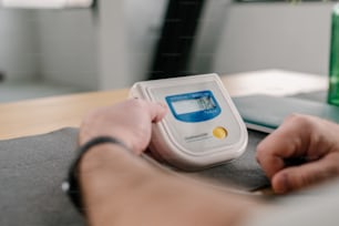 a person sitting at a table with a blood pressure meter