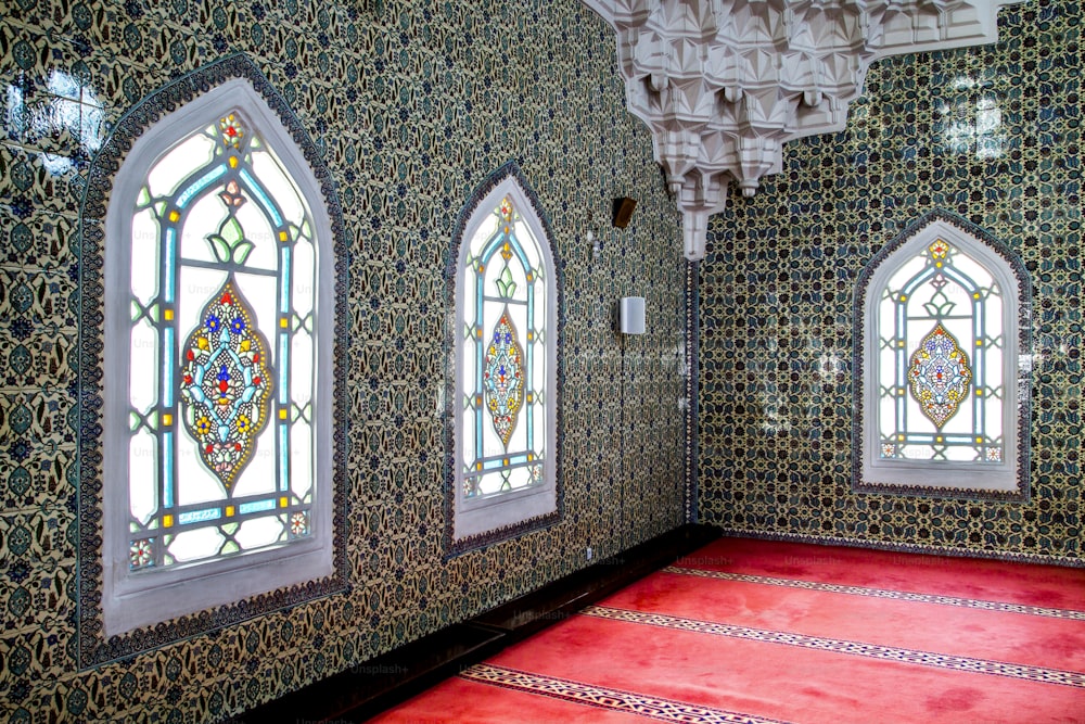 une chambre avec des vitraux et un tapis rouge