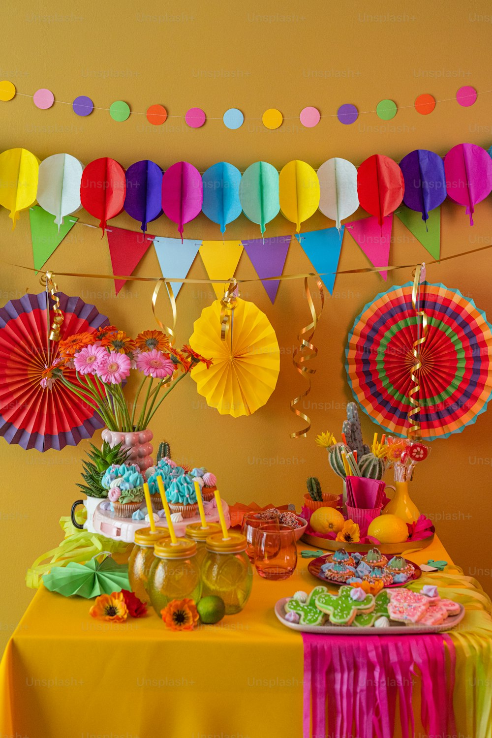 una mesa cubierta con un pastel y cupcakes