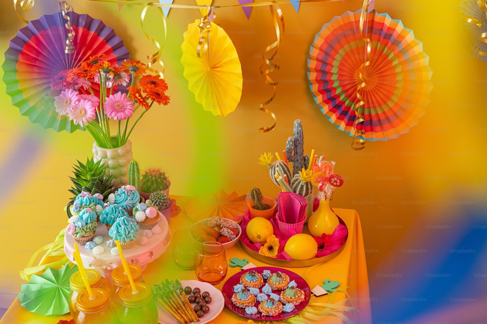 una mesa cubierta con un pastel y cupcakes