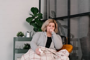 a woman sitting in a chair with a blanket over her face