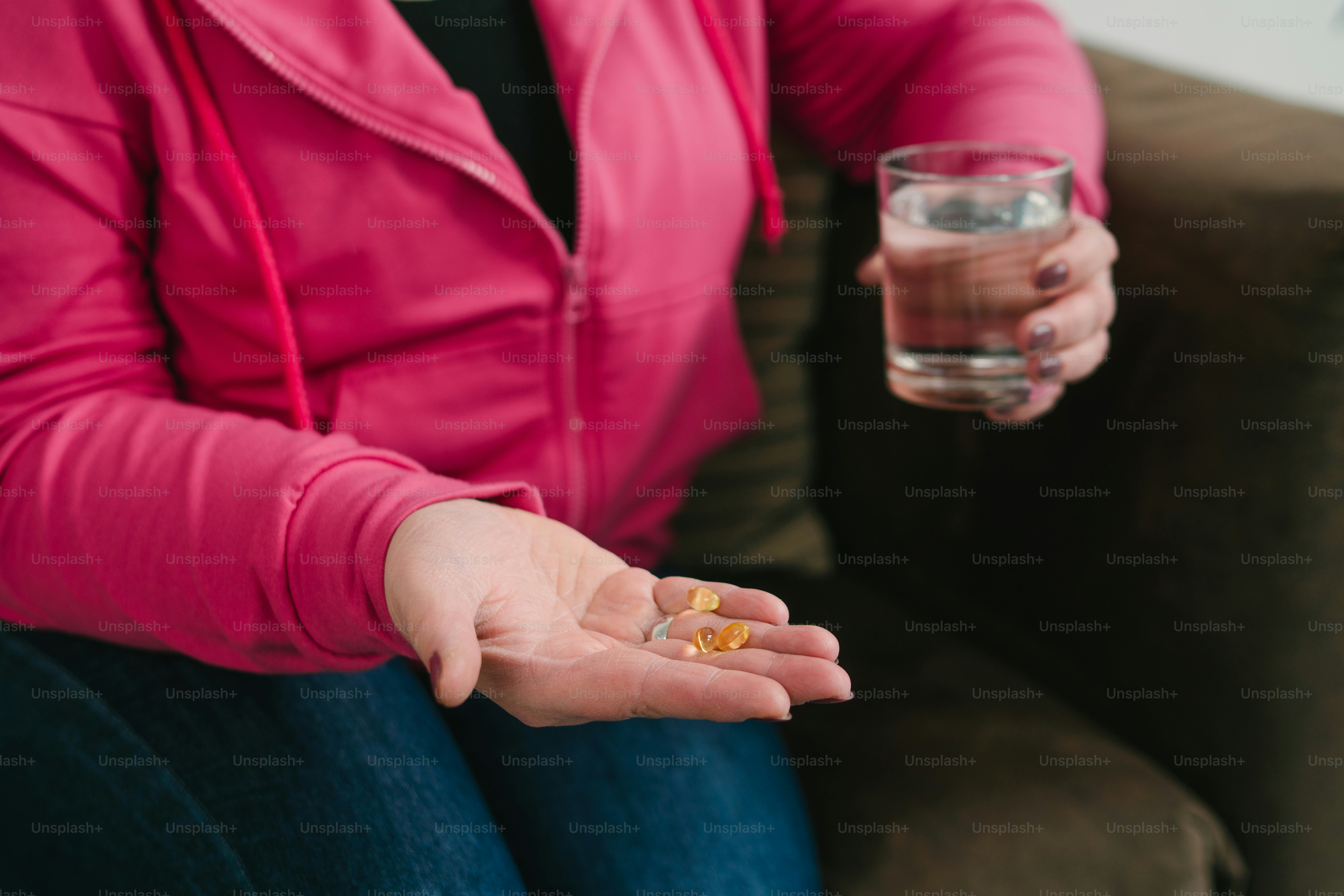 Une femme assise sur un canapé tenant un verre d’eau
