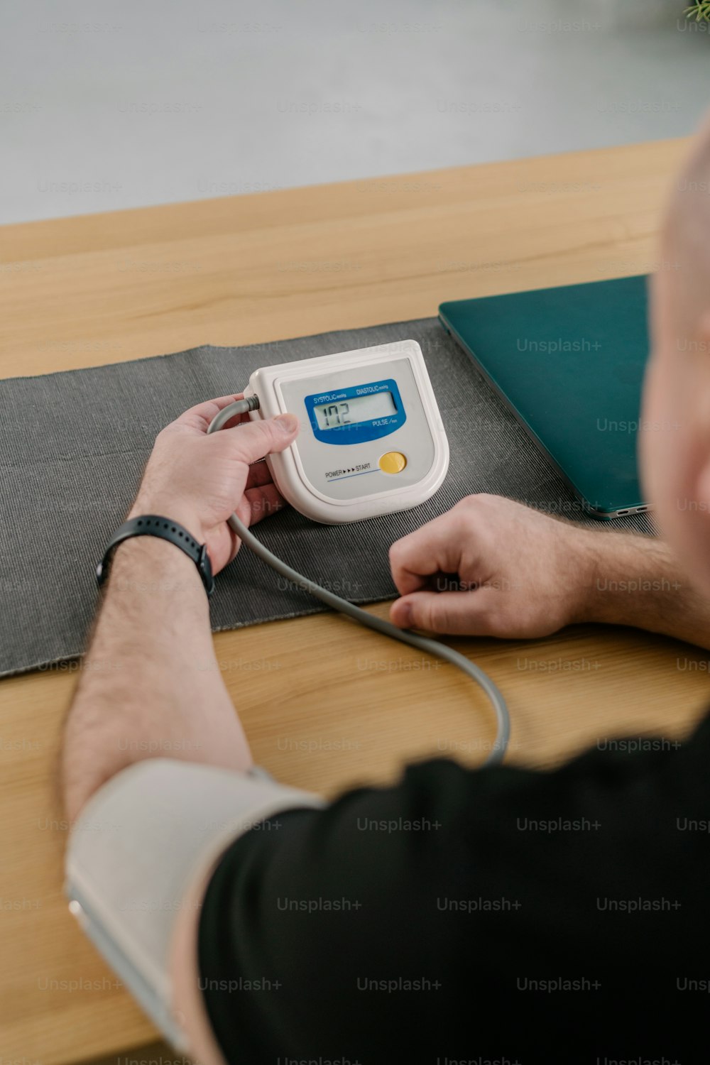 テーブルの上で血圧計を使用している男性