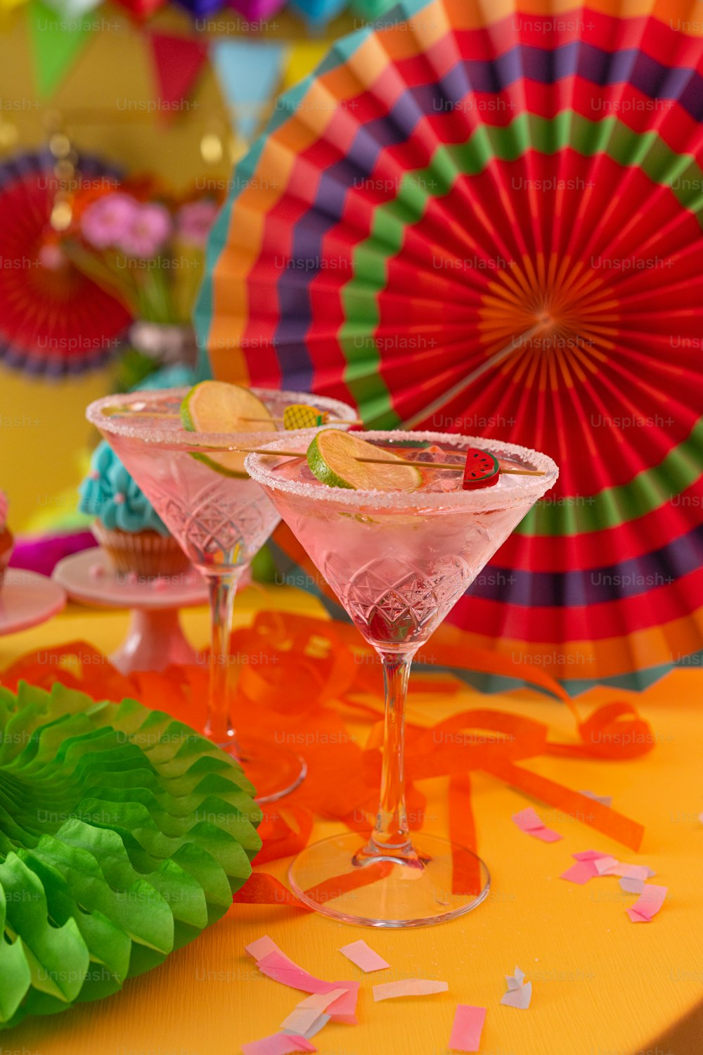Una mesa cubierta con dos vasos de martini llenos de líquido rosa