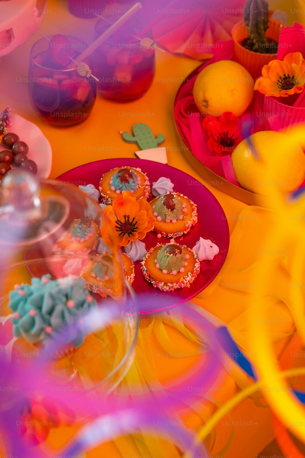 a table topped with a plate of cupcakes covered in frosting