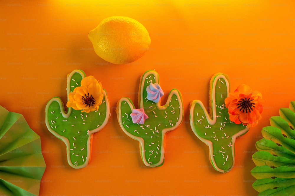 Tres galletas decoradas como cactus y flores sobre una mesa