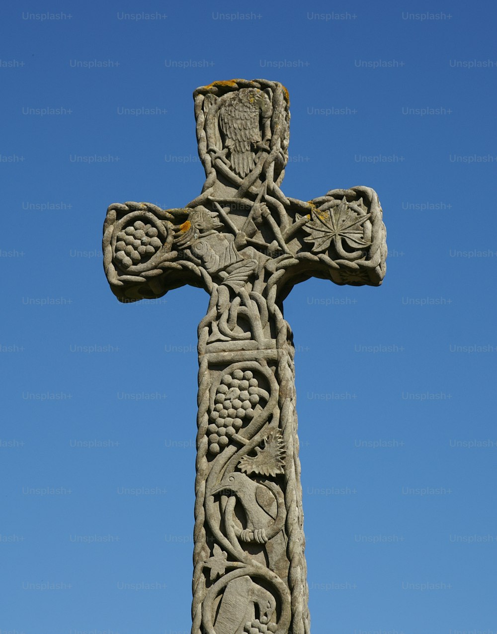 a stone cross with carvings on it against a blue sky