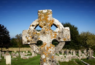 a large stone cross in a cemetery with trees in the background