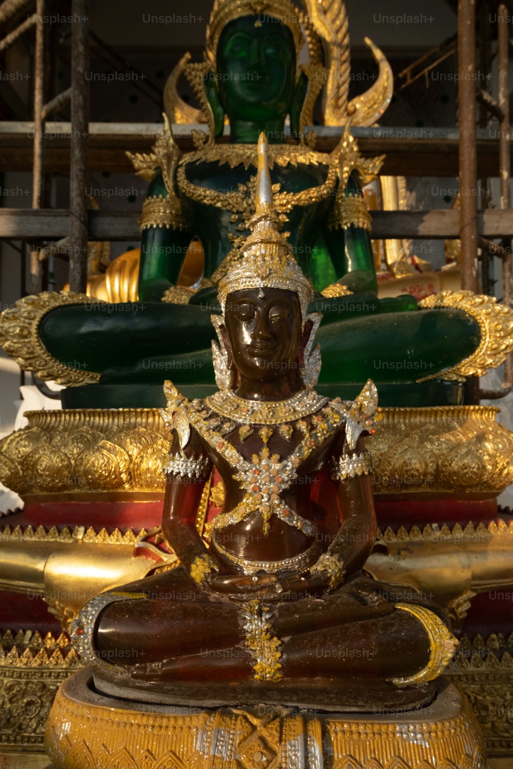 Una estatua de una persona sentada frente a una estatua de Buda