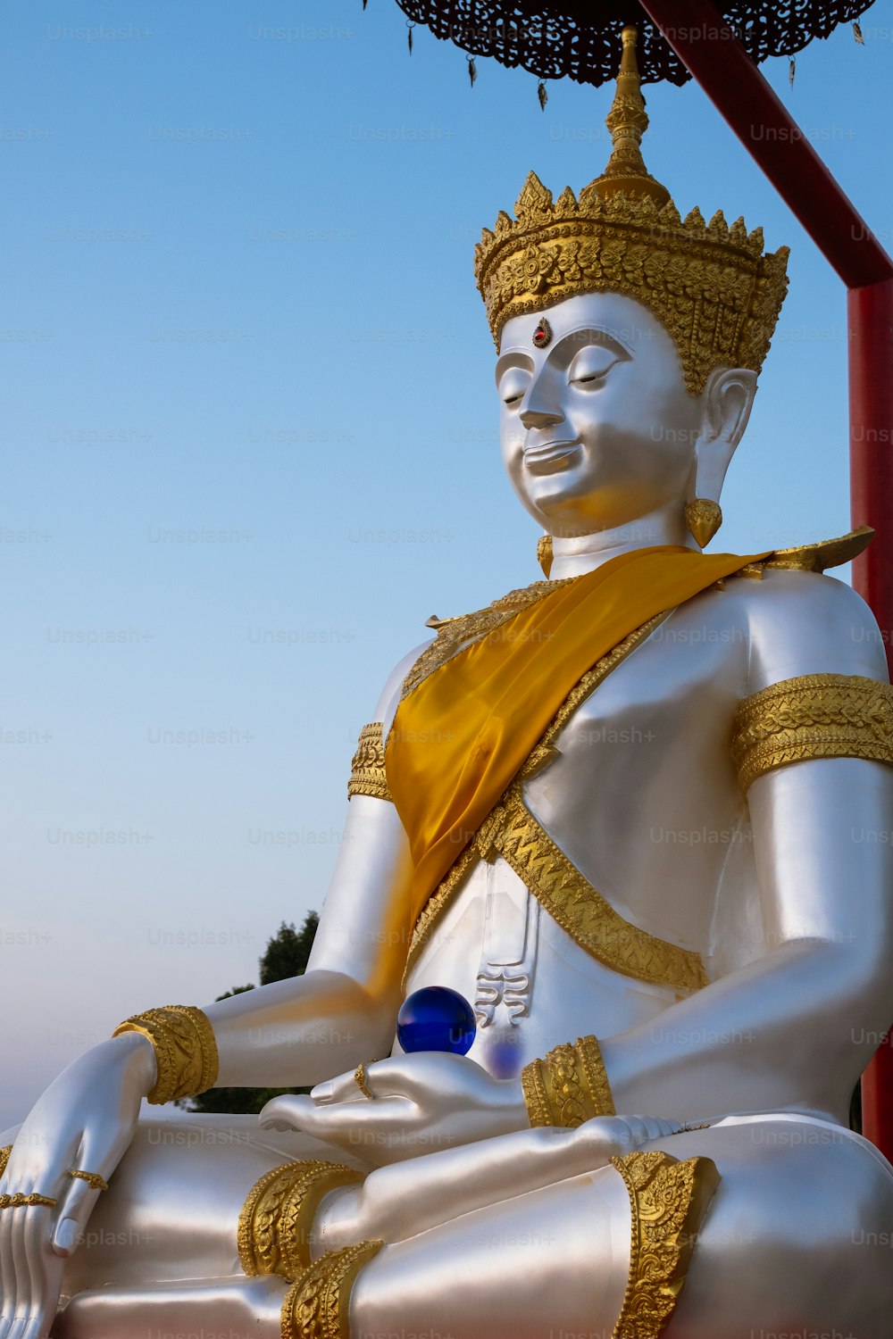 Una gran estatua blanca de Buda sentada bajo un paraguas