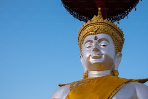 a large white buddha statue sitting under a blue sky
