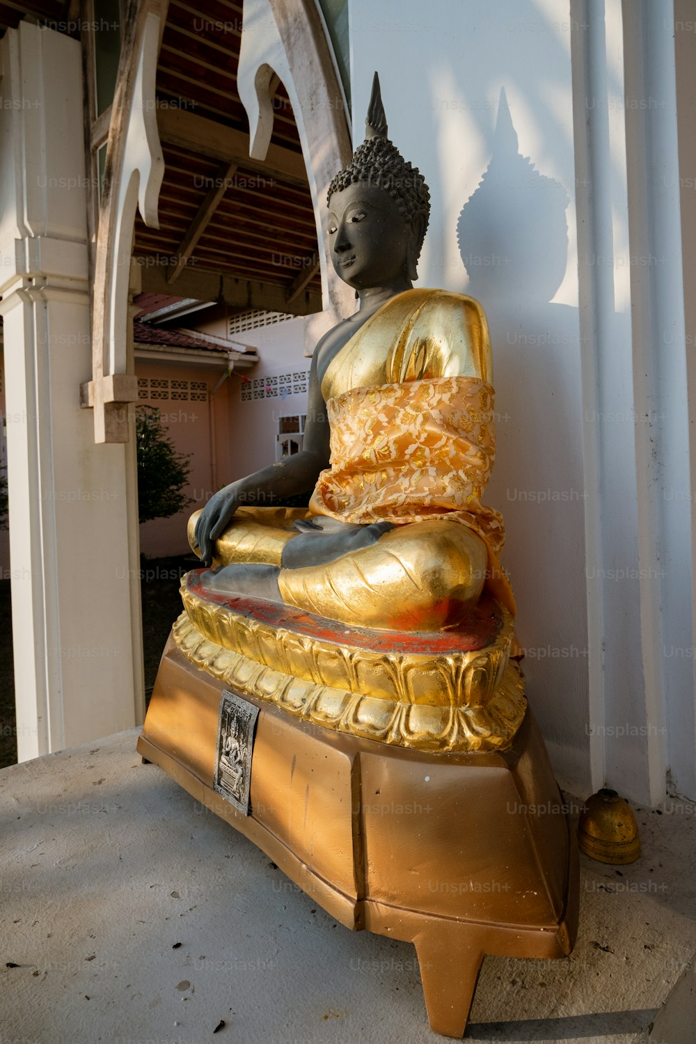 Una statua dorata del Buddha seduta di fronte a un edificio