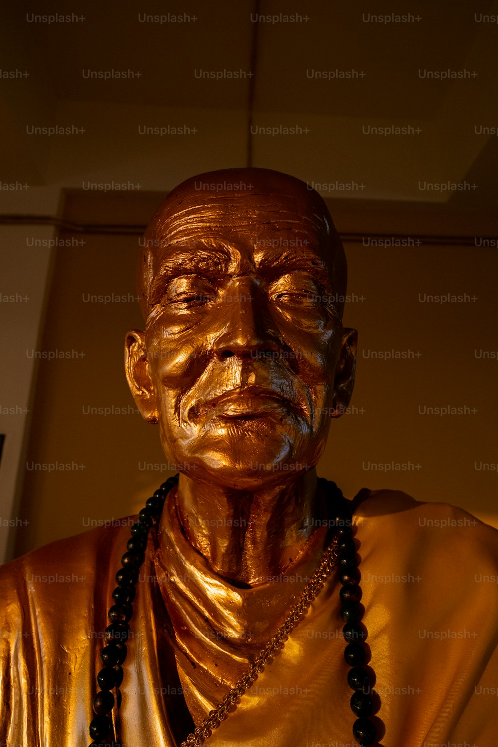 a golden statue of a man with a beaded necklace