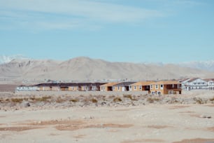 Une rangée de maisons dans un désert avec des montagnes en arrière-plan