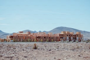 Un edificio en medio de un desierto con montañas al fondo