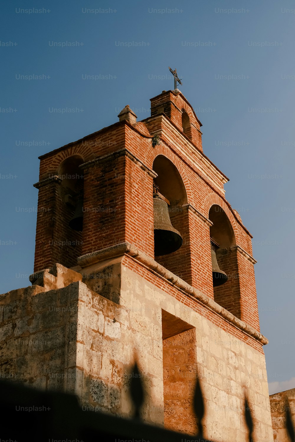una alta torre de ladrillo con una cruz en la parte superior