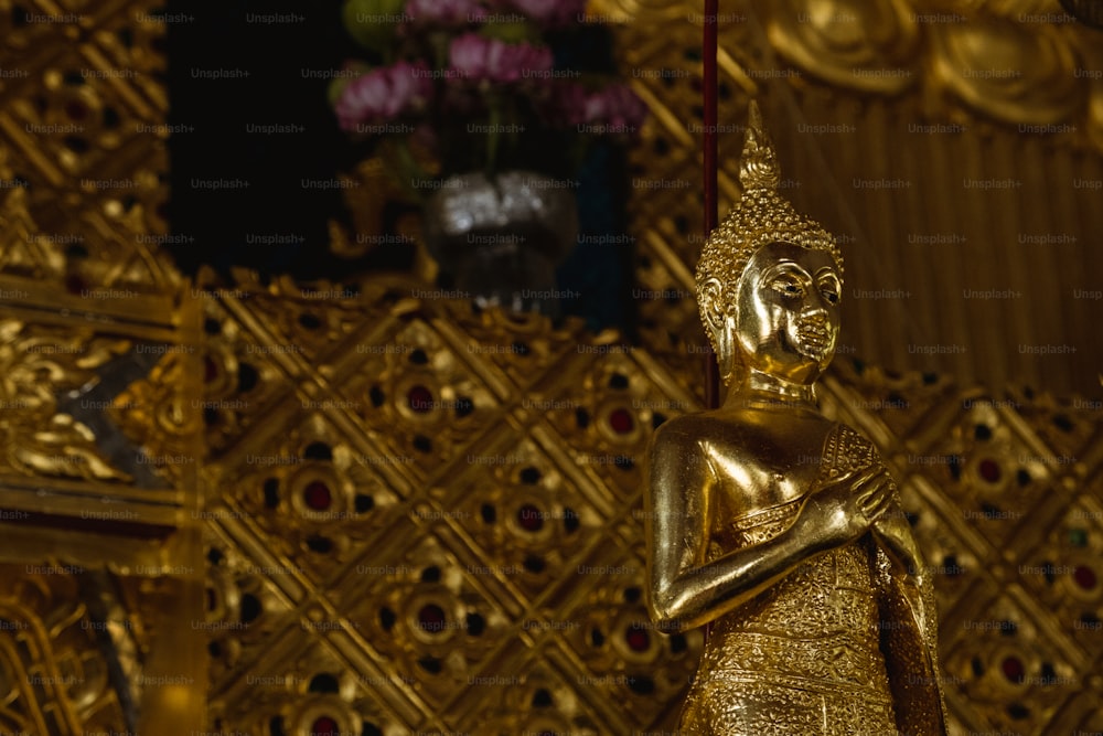 a gold buddha statue sitting in front of a gold wall