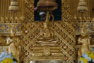 a golden shrine with a buddha statue and flowers