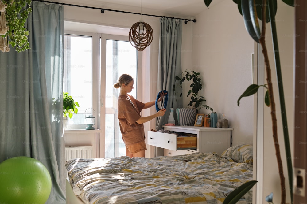 Una mujer parada en un dormitorio sosteniendo un par de tijeras