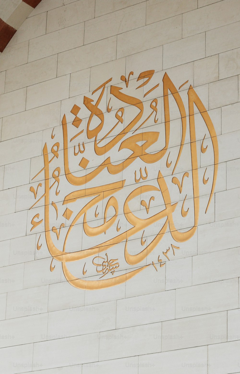 a white brick wall with a gold and white calligraphy on it