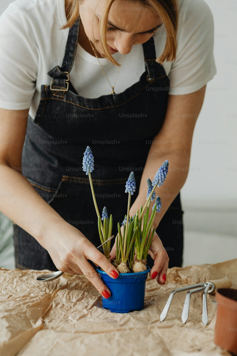 Une femme organise des fleurs dans un pot bleu