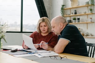 a man and woman sitting at a table looking at papers