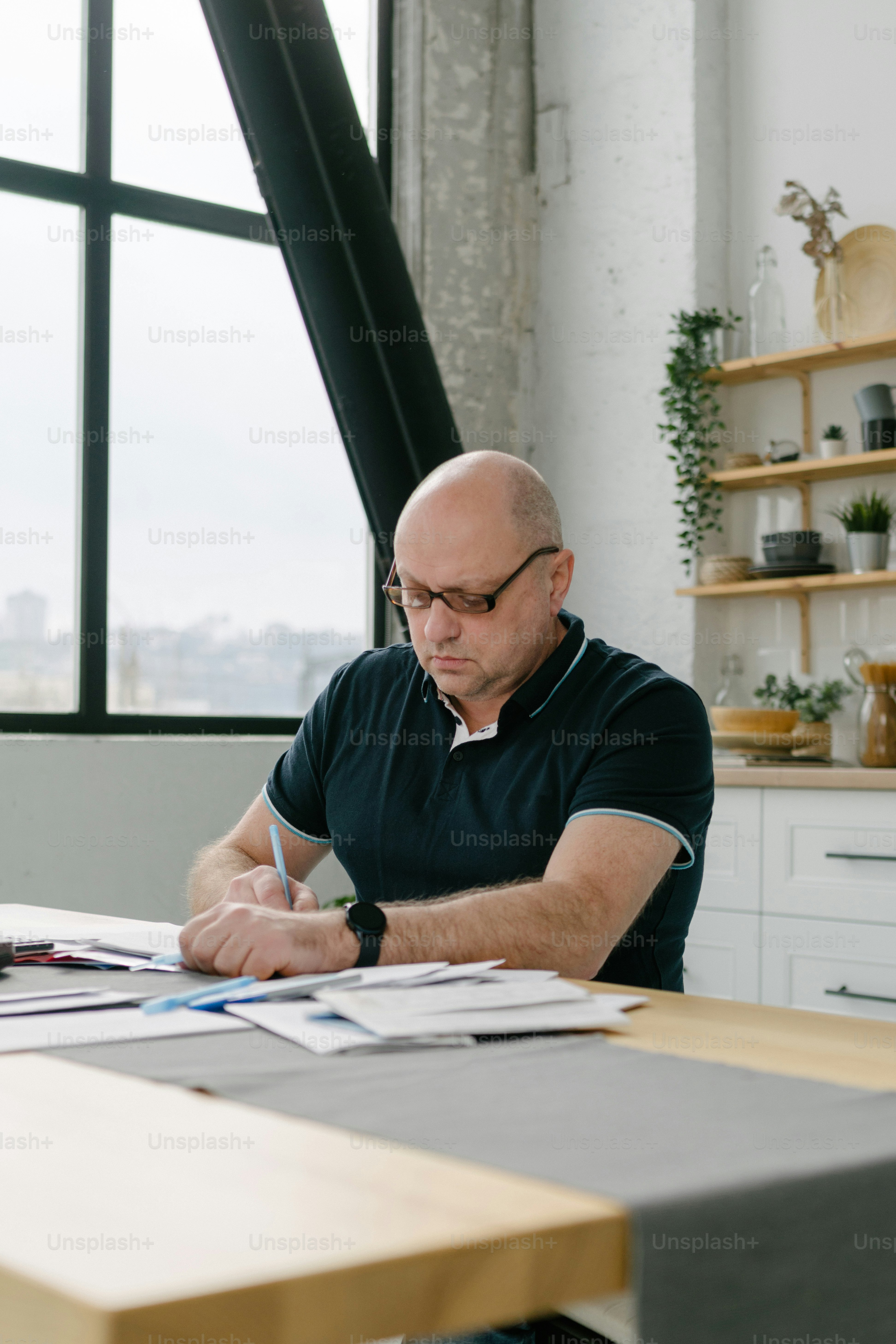 Ein Mann sitzt an einem Tisch und schreibt auf ein Blatt Papier