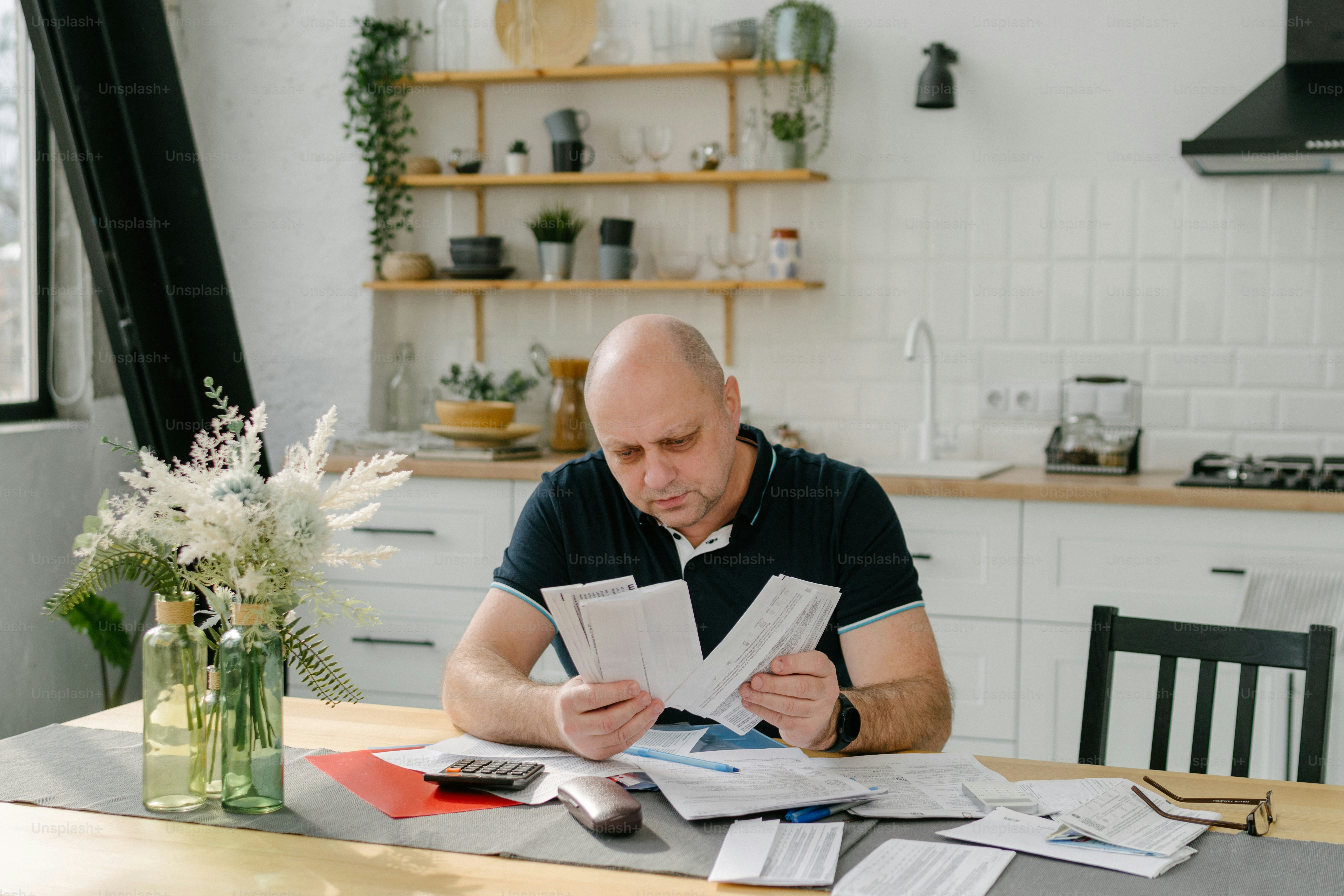 a man sitting at a table with papers and a calculator