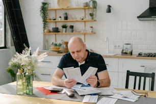Un hombre sentado en una mesa con papeles y una calculadora