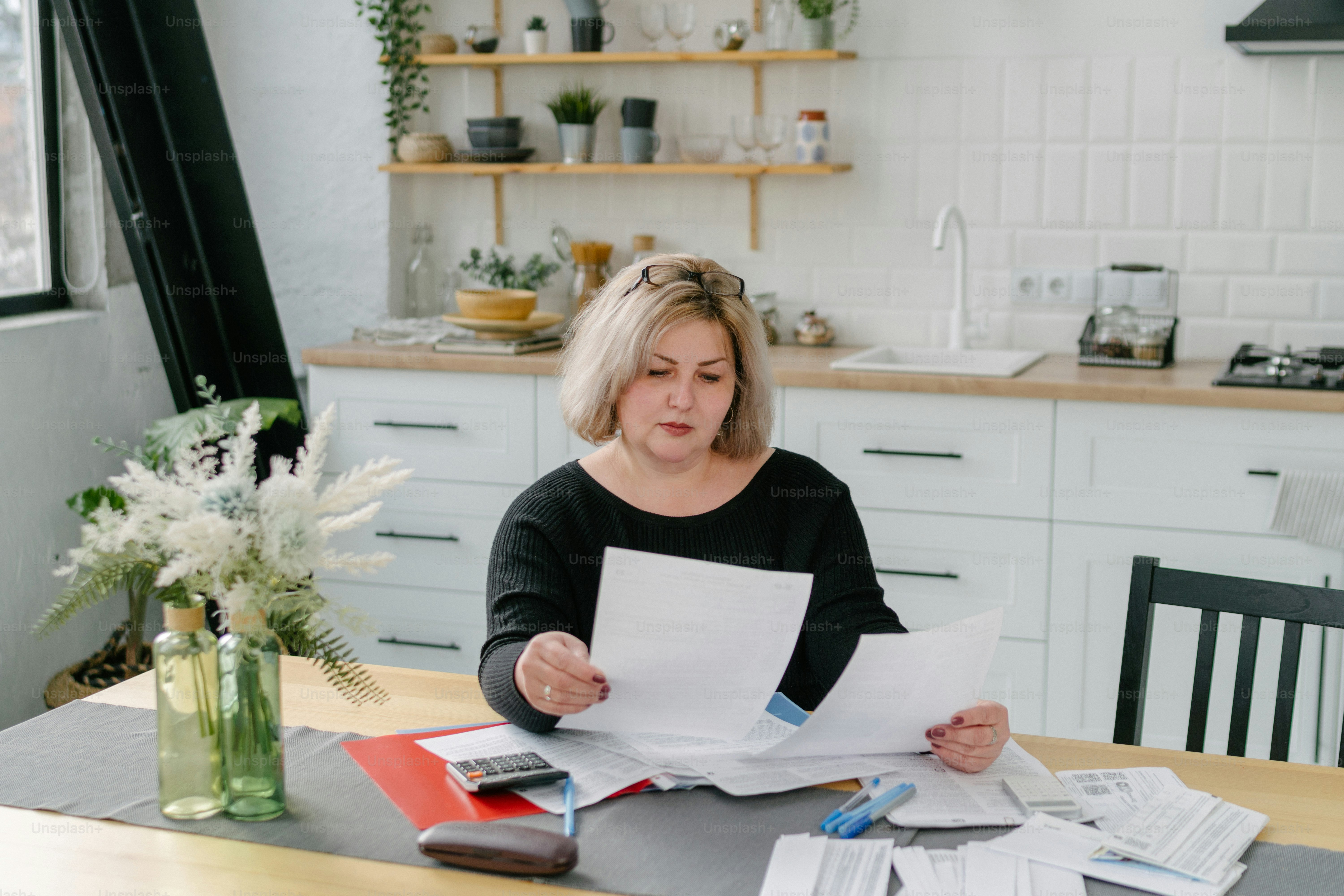 a woman sitting at a table with papers and a calculator
